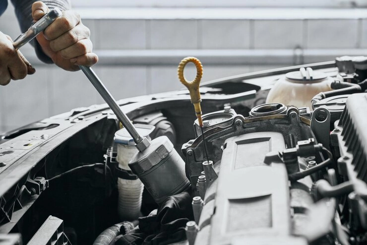 دست یک مکانیک در حال بررسی داخل کاپوت خودرو - تأثیر روغن موتور بر عملکرد خودرو
