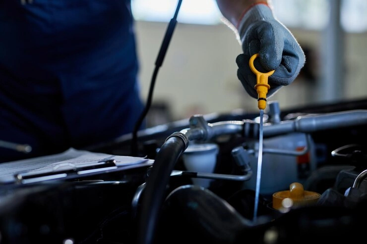 فروش روغن موتور آنلاین - مکانیک در حال بررسی میزان روغن موتور خودرو به وسیله گیج 
